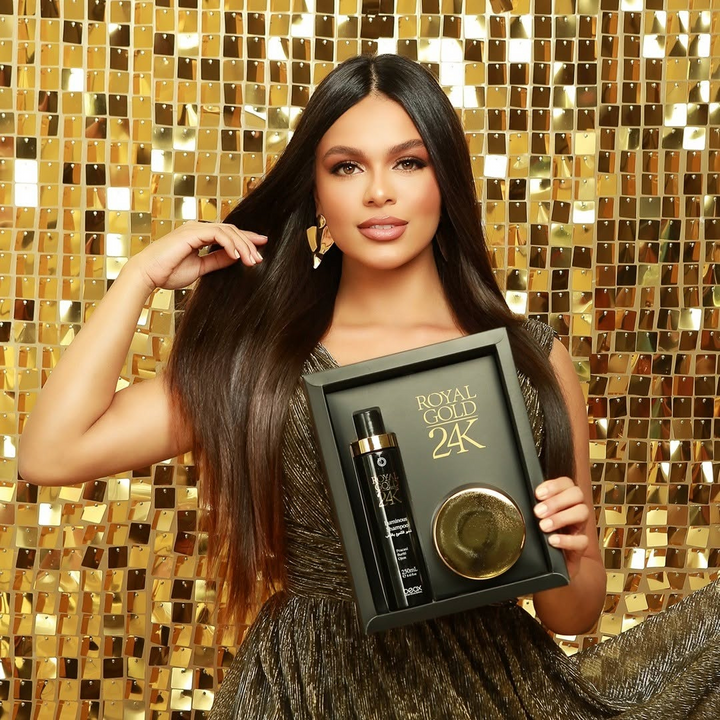 Woman holding a 'Royal Gold 24K' hair care product set against a gold mosaic background
